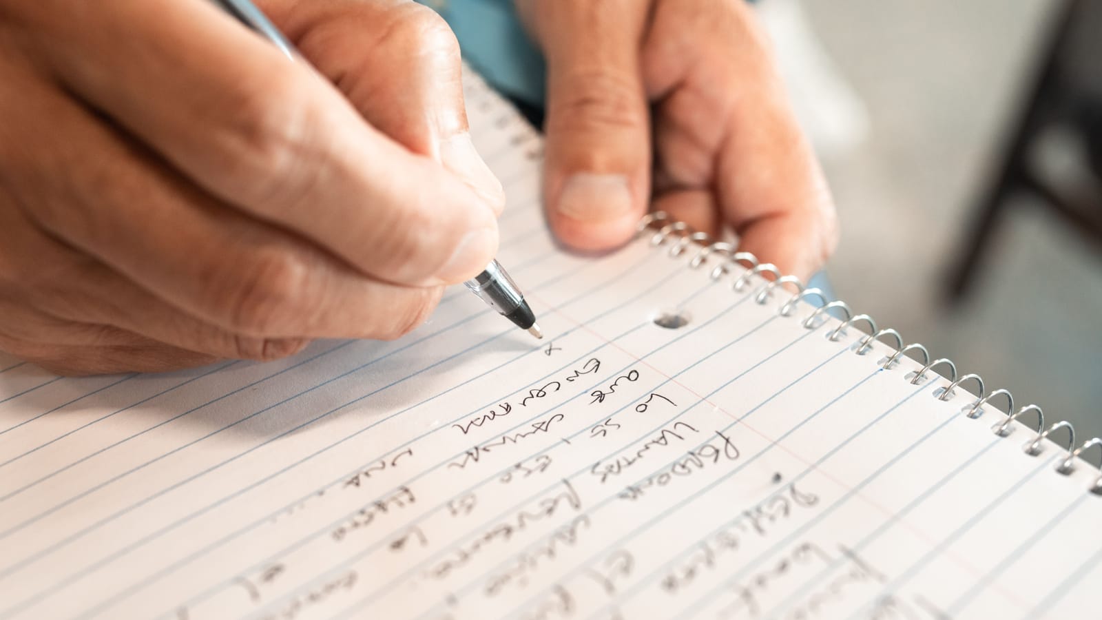 Eine KI-Wissensdatenbank macht das Wissen im Unternehmen fragbar, bevor erfahrene Mitarbeiter aufhören. Hände schreiben handschriftliche Notizen in ein liniertes Heft.
